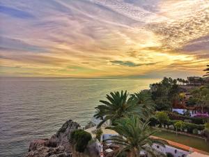 widok na ocean o zachodzie słońca z palmami w obiekcie Carabeo Vista Mar w mieście Nerja