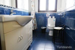 a blue tiled bathroom with a sink and a toilet at Chalet Las Calzadas - Jardín, parking y vistas increíbles in San Vicente de la Barquera +35 photos