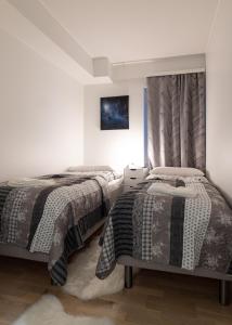 a bedroom with two beds and a painting on the wall at Apartment Loimu C75 in Rovaniemi