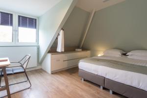 a bedroom with a bed and a desk and a window at B&B - Brasserie De Lindeboom in Serooskerke