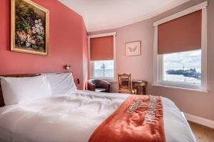 Amsterdam Hotel Brighton Seafront في برايتون أند هوف: غرفة نوم بسرير ابيض ونوافذ