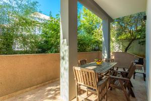 a patio with a wooden table and chairs and trees at Apartments Sunset in Njivice