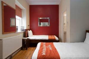 Amsterdam Hotel Brighton Seafront في برايتون أند هوف: غرفة نوم بسريرين وجدار احمر