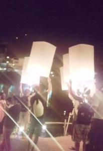 a group of people holding up white lanterns at night at NorthLands House Hotel in Chiang Mai