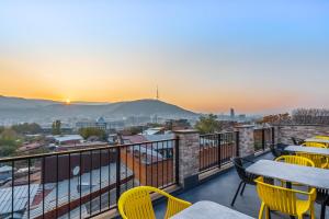 a balcony with tables and chairs and the sunset at Tbilisi Story Hotel in Tbilisi City