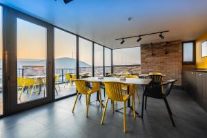 a dining room with yellow chairs and tables and windows at Tbilisi Story Hotel in Tbilisi City