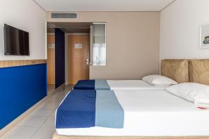 a bedroom with a large bed and a television at Iu-á Hotel in Juazeiro do Norte