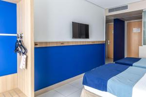 Cette chambre comprend un lit et une télévision murale. dans l'établissement Iu-á Hotel, à Juazeiro do Norte