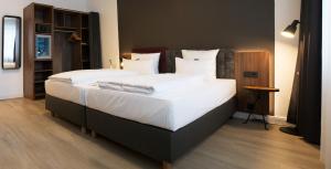 1 dormitorio con 1 cama grande con sábanas y almohadas blancas en Hotel am Schlosstheater en Fulda