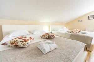 Zimmer mit 3 Betten mit weißer Bettwäsche und Kissen in der Unterkunft F Apartmani Kragujevac in Kragujevac