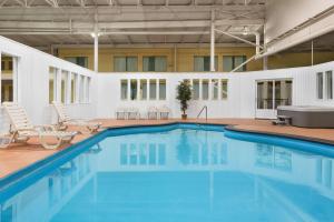 une grande piscine avec des chaises et une baignoire dans l'établissement Hotel Days Inn Blainville & Centre de Conférence, à Blainville