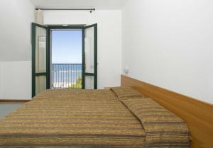 Bett in einem Zimmer mit einem großen Fenster in der Unterkunft Residence Stella Marina in Cupra Marittima