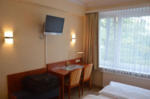 a hotel room with a desk and a television on the wall at Hotel Wikinger Hof in Hamburg