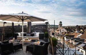 a patio with a couch and an umbrella on a balcony at Widder Hotel - Zurichs luxury hideaway in Zurich