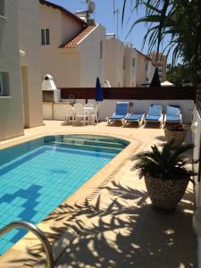 a swimming pool with chairs and a house at Maricosta Villas in Protaras