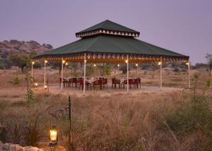 un cenador con mesas y luces en un campo en Jawai Leopard Safari Lodge, en Bera