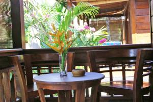 um vaso com uma planta sobre uma mesa com cadeiras em Colour Cottage em Gili Air