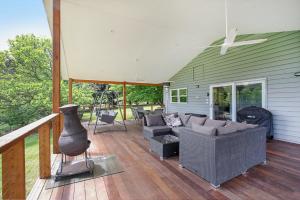 a screened in porch with a couch and a fireplace at Indie's Run in Wandiligong