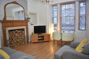 a living room with a fireplace and a television at Rose Street - Watchmakers Apartment in Edinburgh