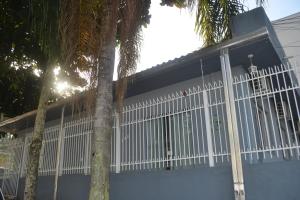 a white fence in front of a house with palm trees at CASA PRAIA A 600m DO MAR in Balneário Camboriú