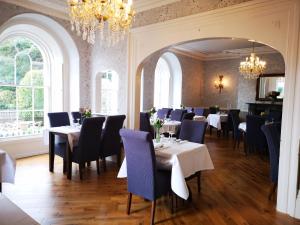 a dining room with tables and chairs and a chandelier at Anglesey Hotel in Gosport