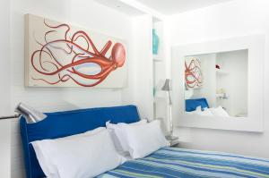 Un dormitorio con una cama azul y una pintura en la pared en Capo la Gala Hotel&Wellness, en Vico Equense