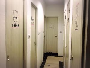 um corredor com quatro portas com desenhos nas paredes em Chitow Hostel em Kaohsiung