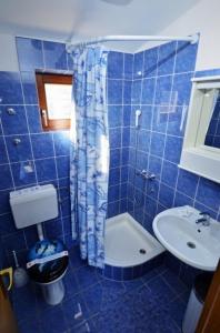 Baño de azulejos azules con aseo y lavamanos en Apartments Sara, en Tisno