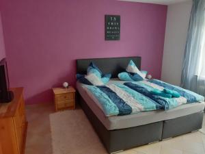 ein Schlafzimmer mit einem Bett mit einer lila Wand in der Unterkunft Ferienwohnung Birgit in Winterberg
