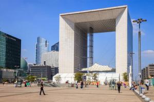 a large building in a city with people walking around at Appartement Lilas Parc 1 - Paris La Défense in Courbevoie