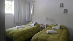 2 camas verdes en una habitación con ventana en Depto Altos del Sol en San Martín de los Andes