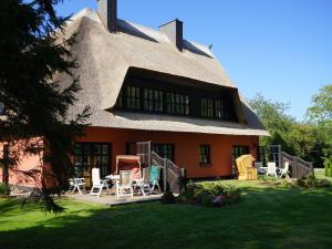 a house with a thatched roof and chairs in the yard at Pferdehof Bela in Nonnevitz