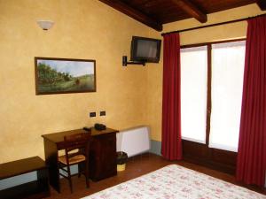 a bedroom with a desk and a television on the wall at Agriturismo Greppi in Crescentino