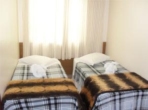 two beds in a room with a window at Parque Hotel de Lambari in Lambari