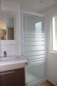 uma casa de banho com uma cabina de duche em vidro e um lavatório. em MAS DES LAVANDES em Sérignan