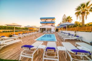 una piscina con sillas y sombrillas frente a un complejo en Emi Seaside, en Amoudara Herakliou