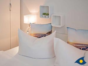 Habitación con cama con almohadas blancas. en Villa Lucie Else Whg 04 Backbord, en Heringsdorf