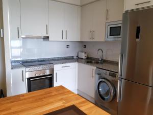 a kitchen with white cabinets and a stainless steel refrigerator at Apto. Vista Playa Poniente in Gijón