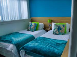 1 dormitorio con 2 camas, paredes azules y ventana en The Beaucliffe, en Blackpool