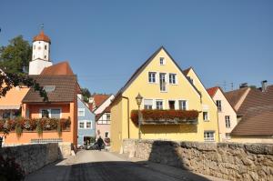 una calle en una ciudad con casas amarillas y una torre del reloj en Hotel Gasthof zum Goldenen Lamm en Harburg