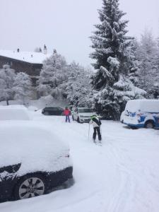 une personne à skis dans la neige à côté d'une voiture dans l'établissement Grain d'Or - Studio 007, à Verbier