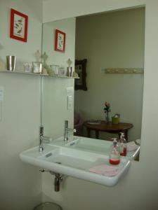 La salle de bains est pourvue d'un lavabo blanc et d'un miroir. dans l'établissement Chez L'Antiquaire, à Hauterives