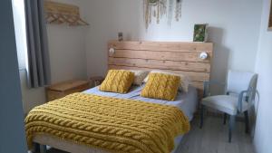 um quarto com uma cama com um cobertor amarelo e uma cadeira em Le jardin des Écureuils em Démuin