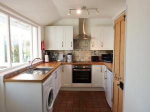 Nitonにある2 Farm Cottagesの白いキャビネットと食器洗い機付きのキッチンが備わります。