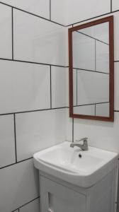 a white bathroom with a sink and a mirror at Andalus beach residence in Marang