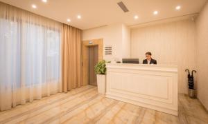 a woman standing at a reception desk in a lobby at 14 Floor Hotel in Yerevan