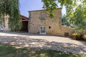 un grande edificio in pietra con una porta bianca in un cortile di Le Logis du Château a Vieillevigne