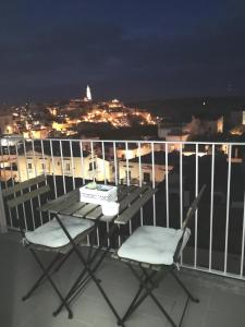 stół i 2 krzesła na balkonie w nocy w obiekcie Dimore Pietrapenta Apartments, Suites & Rooms - Via Lucana 223, Via Piave 23, Via Chiancalata 16 w mieście Matera