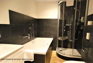 een badkamer met een bad en een douche bij Hotel Sewenig in Müden