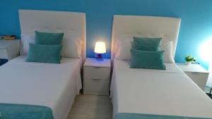 two twin beds in a room with blue walls at Pensión Mar Azul in Santiago de Compostela